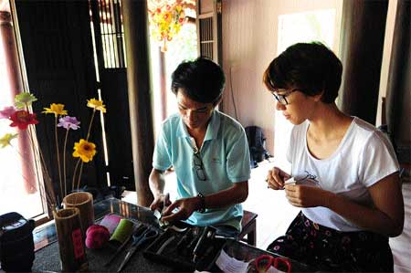 Making the cut: An artisan demonstrates the art of lotus paper flowers to an interested visitor. 
